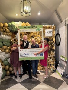 Sarah Spedding, Leroy Philbrook, Pete Sims, from Blue Rock IT, and Tracy Heatley, pointing to the Blue Rock IT branding who were sponsors of the Freshies Awards 2025